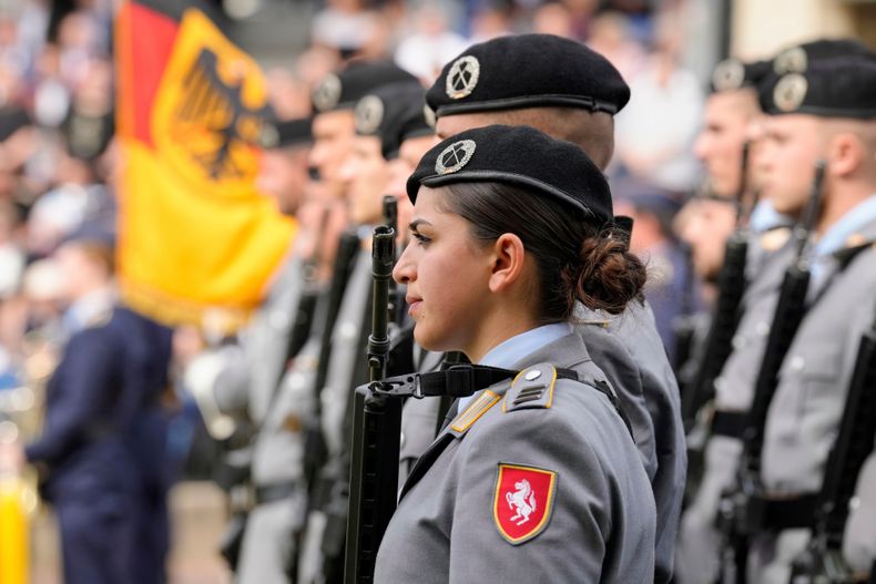 Una mujer soldado observa a los nuevos reclutas de la Bundeswehr del Ejército alemán asistir a una ceremonia para prestar juramento frente al Parlamento de Renania del Norte-Westfalia en Düsseldorf, Alemania, el jueves 4 de septiembre de 2025. (AP Foto/Martin Meissner)