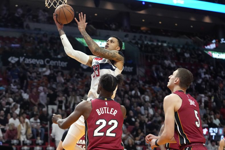 El alero de los Wizards de Washington, Kyle Kuzma ataca el aro rebasando al escotla del Heat de Miami Jimmy Butler (22), y al alero Nikola Jovic durante la primera mitad del juego de baloncesto de la NBA, el domingo 10 de marzo de 2024, en Miami. (AP Foto/Lynne Sladky)