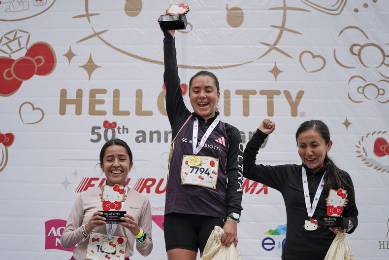 Miriam Ramos, izquierda, Paulina Plascencia Cruz, centro, y Valeria Monroy celebran en el podio después de ganar una carrera durante la celebración del 50 aniversario del personaje japonés Hello Kitty, en la Ciudad de México, el domingo 13 de octubre de 2024. (Foto AP/Aurea Del Rosario)