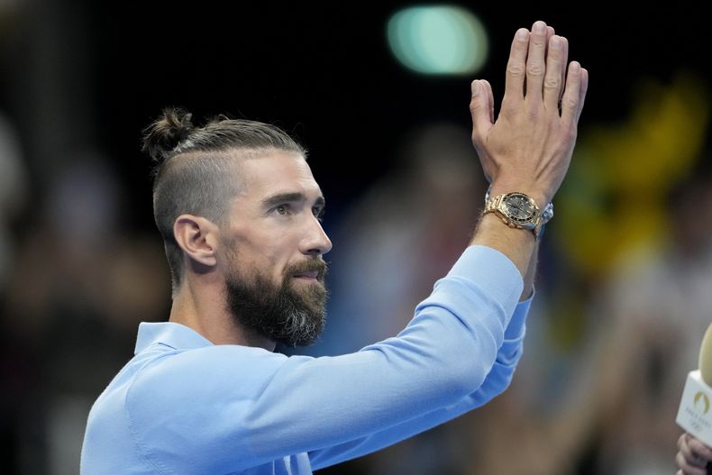 El retirado nadador Michael Phelps saluda al público en la piscina de los Juegos Olímpicos de París, el domingo 28 de julio de 2024, en Nanterre, Francia. (AP Foto/Matthias Schrader)