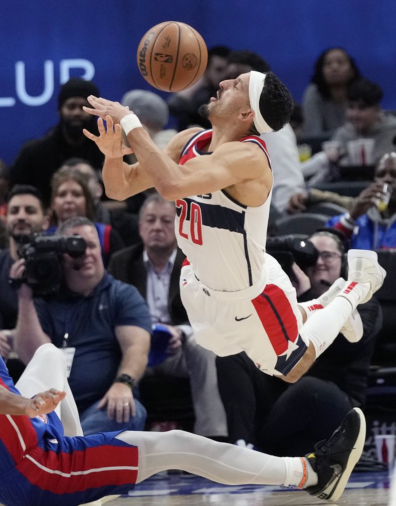 Landry Shamet (20), de los Wizards de Washington, pierde el control del balón al tropezar con Jaden Ivey, de los Pistons de Detroit durante la segunda mitad del juego de baloncesto de la NBA, el lunes 27 de noviembre de 2023, en Detroit. (AP Foto/Carlos Osorio)
