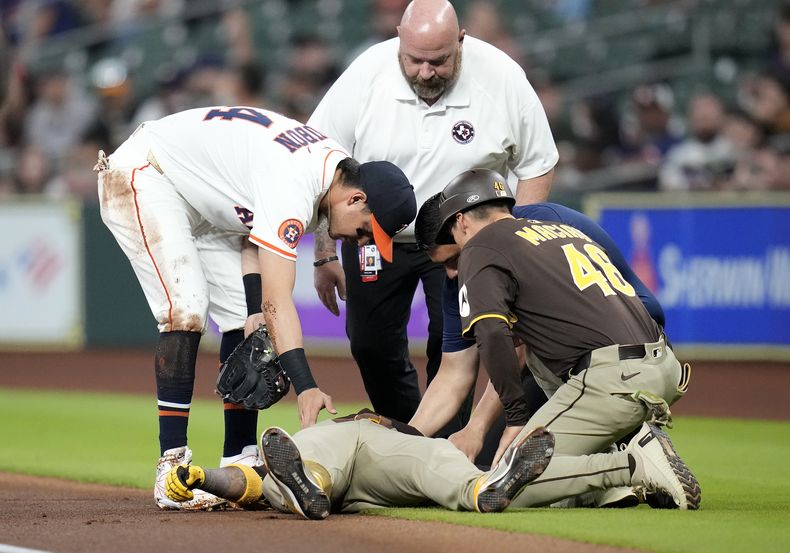 Luis Arráez, de los Padres de San Diego, yace tendido en terreno de foul a un costado de primera base después de una colisión con Mauricio Dubón, izquierda, de los Astros de Houston, mientras el coach de primera base de Padres, David Macias (46), junto con el entrenador de los Astros revisan al pelotero venezolano durante la primera entrada del juego de béisbol de Grandes Ligas el domingo 20 de abril de 2025, en Houston. (AP Foto/Karen Warren)