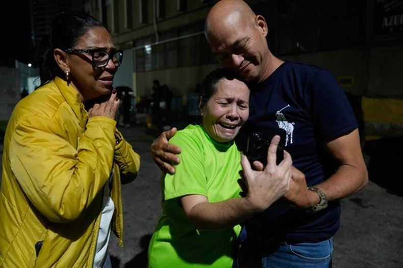 Morelba Delgado, en el centro, habla con un familiar por celular tras ser liberada del centro de detención Zona 7 de la Policía Nacional Bolivariana, el sábado 14 de febrero de 2026, en Caracas, Venezuela. (AP Foto/Ariana Cubillos)