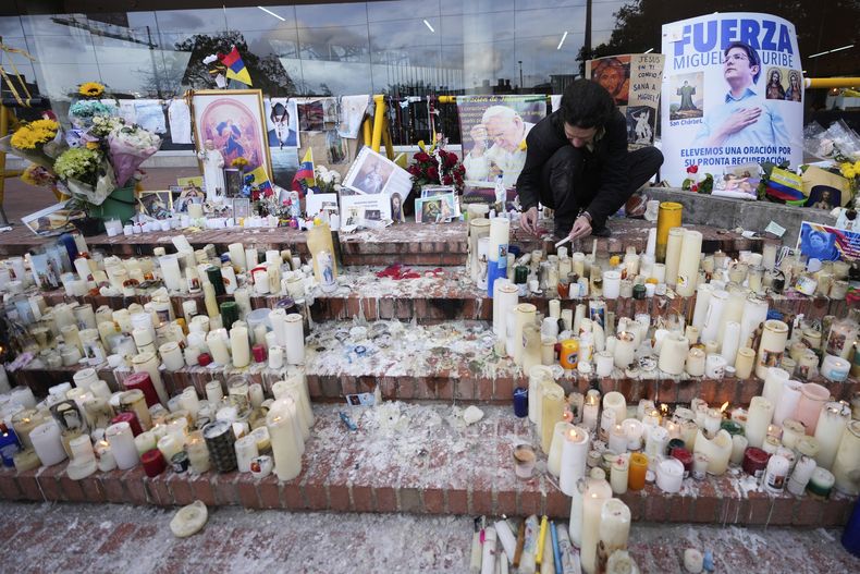Un hombre enciende velas en un altar que se instaló en honor al senador colombiano Miguel Uribe Turbay, quien está siendo atendido luego de recibir un disparo en un mitin político, en Bogotá, Colombia, el miércoles 18 de junio de 2025. (AP Foto/Fernando Vergara)
