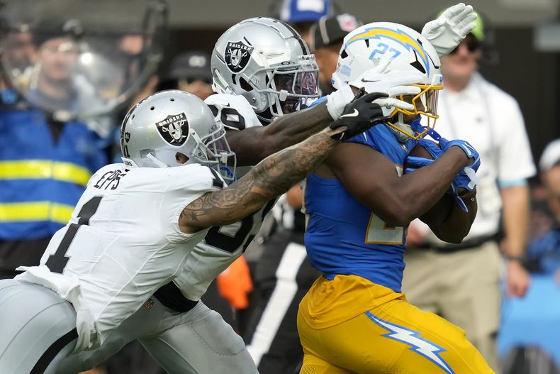 J.K. Dobbins, derecha, running back de los Chargers de Los Ángeles, es alzanzado por el safety Marcus Epps, izquierda, y el cornerback Nate Hobbs, de los Raiders de Las Vegas, durante la segunda mitad del juego de la NFL del domingo 8 de septiembre de 2024, en Inglewood, California. (AP Foto/Ashley Landis)