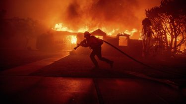 Un bombero lucha contra el incendio Palisades mientras quema una estructura en el vecindario Pacific Palisades de Los Ángeles, el martes 7 de enero de 2025. (Foto AP/Ethan Swope)