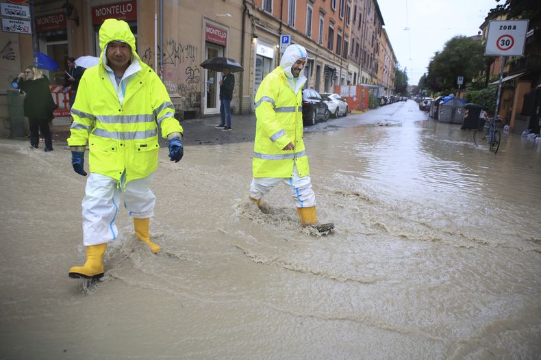 Dos personas cruzan una calle anegada en Bolonia, Italia, el 16 de mayo de 2023. (Michele Nucci/LaPresse via AP)