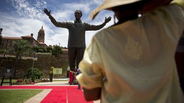 americateve | Una mujer observa una estatua de bronce de 9 metros del ex presidente sudafricano Nelson Mandela en Pretoria, el lunes 16 de diciembre del 2013. (AP Foto/Matt Dunham)