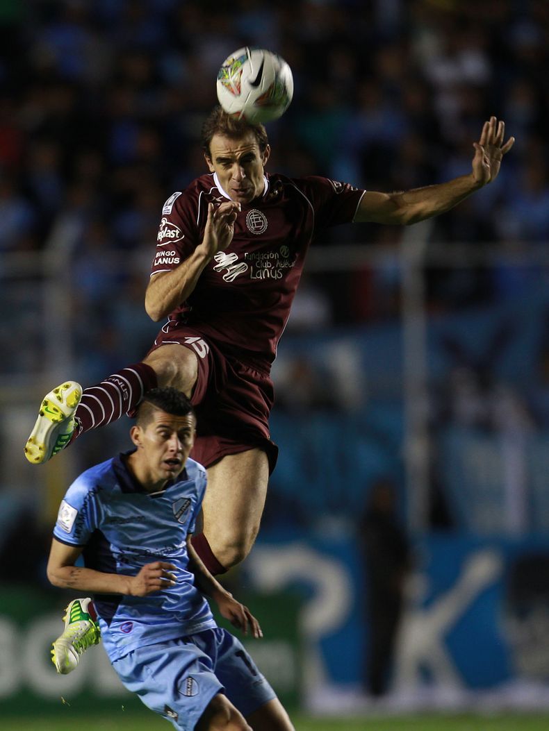 Leandro Somoza del Lan&uacute;s de Argentina (arriba) disputa un bal&oacute;n con Juan Carlos Arce del Bol&iacute;var de Bolivia en los cuartos de final de la Copa Libertadores el jueves 15 de mayo de 2014. (AP Foto/Juan Karita)