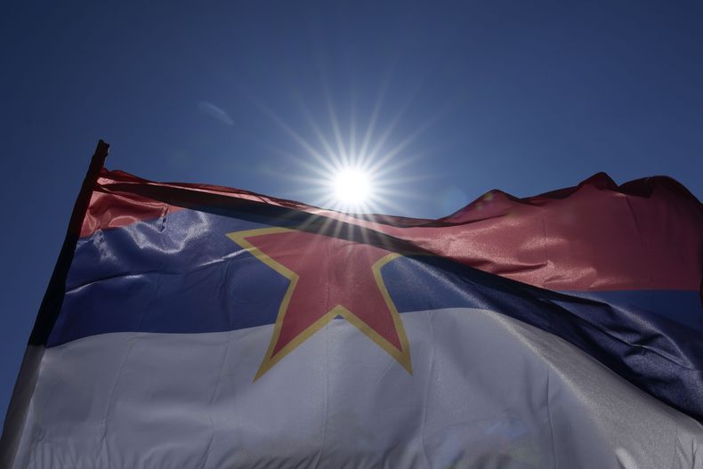 Un hombre sostiene una bandera serbia con la estrella comunista de cinco picos durante la ceremonia del aniversario 80 de la liberación de Belgrado de la ocupación Nazi en la Segunda Guerra Mundial en Belgrado, Serbia, el domingo 20 de octubre de 2024. (AP Foto/Darko Vojinovic)