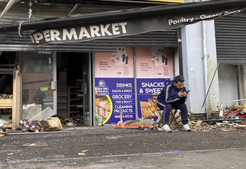 Abdelkader Mohamad Al Alloush, propietario del supermercado Sham, se sienta afuera de su tienda en Belfast, Irlanda del Norte, el martes 6 de agosto de 2024, tras los violentos disturbios que sacudieron la nación en la última semana. (Rebecca Black/PA vía AP)