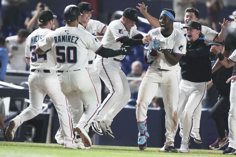 Jesús Sánchez, con banda en la cabeza, de los Marlins de Miami, celebra con sus compañeros de equipo después de batear un triple para dejar tendidos a los Cachorros de Chicago en juego de béisbol de Grandes Ligas, el lunes 19 de mayo de 2025, en Miami. (AP Foto/Lynne Sladky)