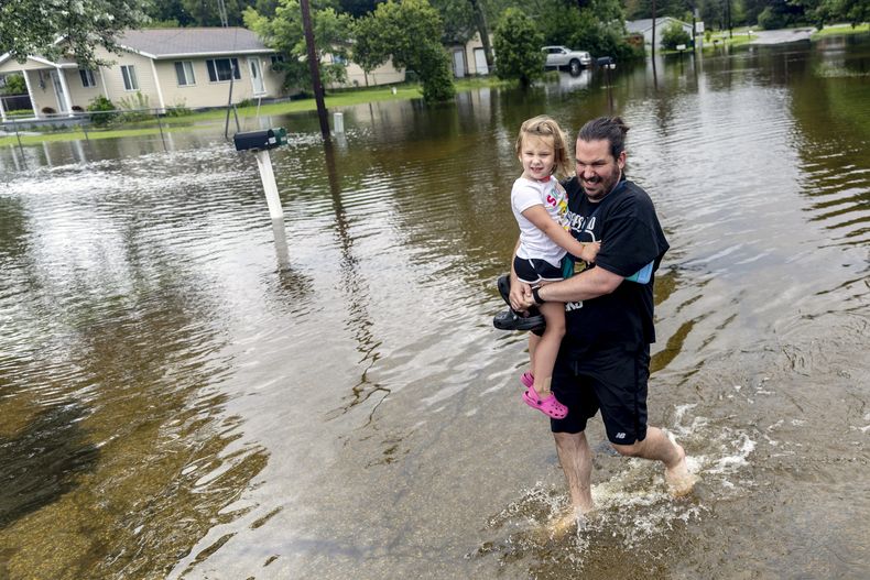 Ryan Tolbert, de Davison, carga a su hija Fiona, de 4 años, por una zona inundada de vuelta a su auto tras recogerla de la casa de su hermana después de lluvias provocadas por los restos del huracán Beryl, el miércoles 10 de julio de 2024 en Genesee Township, Michigan. Es una locura. Ni siquiera puedo describirlo, dijo Tolbert. Nunca he visto nada como esto. Me estalla la cabeza. (Jake May/The Flint Journal via AP)