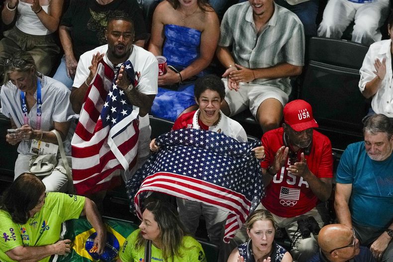 El esposo de Simone Biles, Jonathon Owens, apoya a la gimnasta estadounidense junto a su madre y su padre, Ron y Nellie Biles, durante la final de equipos femeninos de gimnasia artística en los Juegos Olímpicos de verano de 2024, el martes 30 de julio de 2024, en París, Francia. (Foto AP/Morry Gash)