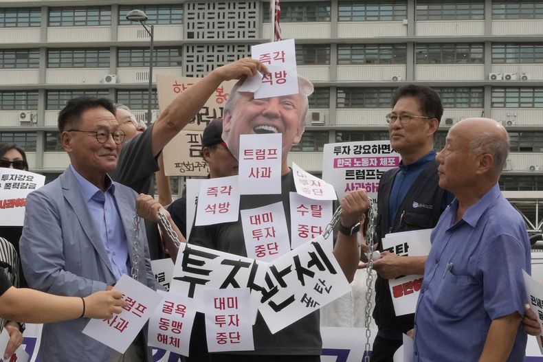 Manifestantes colocan calcomanías a uno de ellos que lleva una máscara del presidente de EEUU, Donald Trump, durante una manifestación contra la detención de trabajadores surcoreanos en una redada de inmigración en Georgia, cerca de la embajada estadounidense en Seúl, Corea del Sur, el martes 9 de septiembre de 2025. Las letras dicen Liberación inmediata y disculpa de Trump. (AP Foto/Ahn Young-joon)