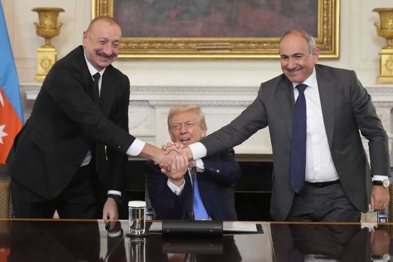El presidente estadounidense, Donald Trump, centro, une sus manos con la del primer ministro armenio Nikol Pashinyan, derecha, y la del presidente de Azerbaiyán Ilham Aliyev en la ceremonia de firma de un acuerdo trilateral en el Comedor de Estado de la Casa Blanca, el viernes 8 de agosto de 2025, en Washington. (AP Foto/Mark Schiefelbein)