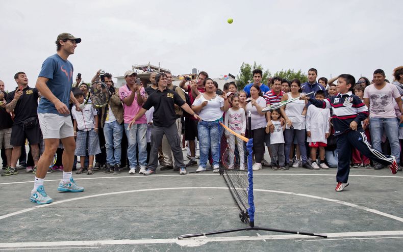 Un ni&ntilde;o devuelve una pelota de tenis al tenista espa&ntilde;ol Rafael Nadal, izquierda, en una visita de Nadal a un barrio pobre en Buenos Aires el martes, 19 de noviembre de 2013. (AP Photo/Natacha Pisarenko)