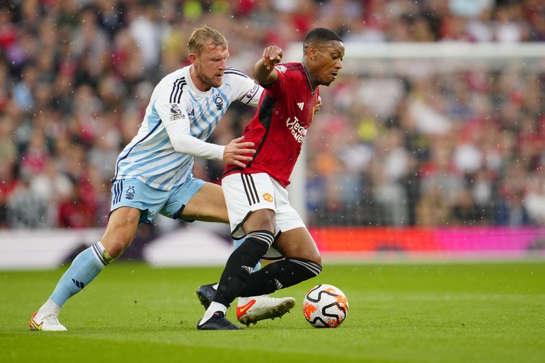 Anthony Martial del Manchester United pelea por el balón con Joe Worrall del Nottingham Forest en el encuentro de la Liga Premier en el Old Trafford el sábado 26 de agosto del 2023. (AP Foto/Jon Super)