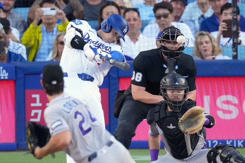 Shohei Ohtani (segundo desde la izquierda), de los Dodgers de Los Ángeles, conecta un jonrón solitario mientras el lanzador abridor de los Rockies de Colorado, Michael Lorenzen (izquierda), y Braxton Fulford observan durante la primera entrada de un partido de béisbol, el martes 7 de julio de 2026, en Los Ángeles. (Foto AP/Mark J. Terrill)