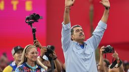 El presidente Nicolás Maduro, acompañado de la primera dama Cilia Flores, con los brazos levantados en el acto de cierre de campaña en Caracas, Venezuela, el jueves 25 de julio de 2024. Maduro busca la reelección para un tercer mandato en las elecciones del 28 de julio. (AP Foto/Fernando Vergara)