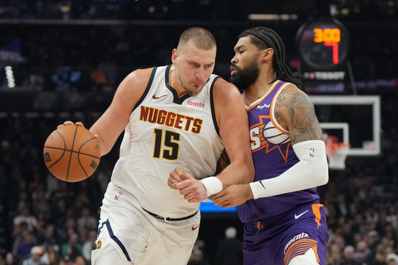 El serbio Nikola Jokic, de los Nuggets de Denver, avanza frente a Nick Richards, de los Suns de Phoenix, el sábado 29 de noviembre de 2025 (AP Foto/Rick Scuteri)