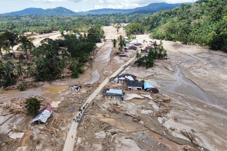Personas caminan por una carretera en un pueblo afectado por una inundación repentina en Batang Toru, Sumatra del Norte, Indonesia, el lunes 1 de diciembre de 2025. (Foto AP/Binsar Bakkara)