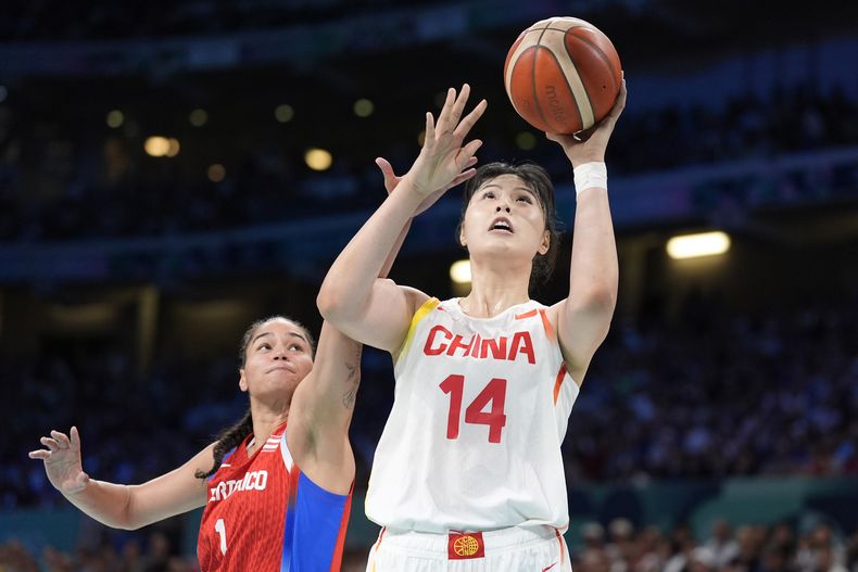 La china Li Yueru (derecha) dispara al aro ante la puertorriqueña Tayra Meléndez en el baloncesto femenino de los Juegos Olímpicos de París, el sábado 3 de agosto de 2024, en Villeneuve-dAscq, Francia. (AP Foto/Michael Conroy)