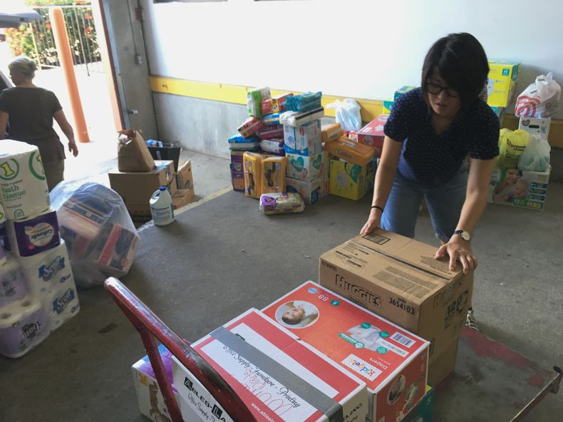 ARCHIVO - Veronica Yoo, voluntaria de Catholic Charities del Valle de Río Grande, carga cajas de donaciones en un carrito, en un almacén de McAllen, Texas el 24 de junio de 2018. (AP Foto/Manuel Valdes, Archivo)