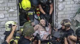 Rescatistas evacúan a un civil herido tras el impacto de un ataque de misiles rusos contra un edificio residencial en Járkiv, Ucrania, el lunes 18 de agosto de 2025. (AP Foto/Andrii Marienko)