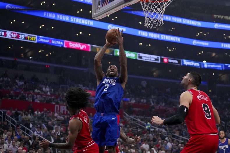 El alero de los Clippers de Los Ángeles, Kawhi Leonard (2), va a la canasta contra el escolta de los Bulls de Chicago, Coby White, a la izquierda, y el pívot Nikola Vucevic (9) durante la primera mitad del partido de baloncesto de la NBA en Los Ángeles, el sábado 9 de marzo de 2024. (AP Foto/Eric Thayer)