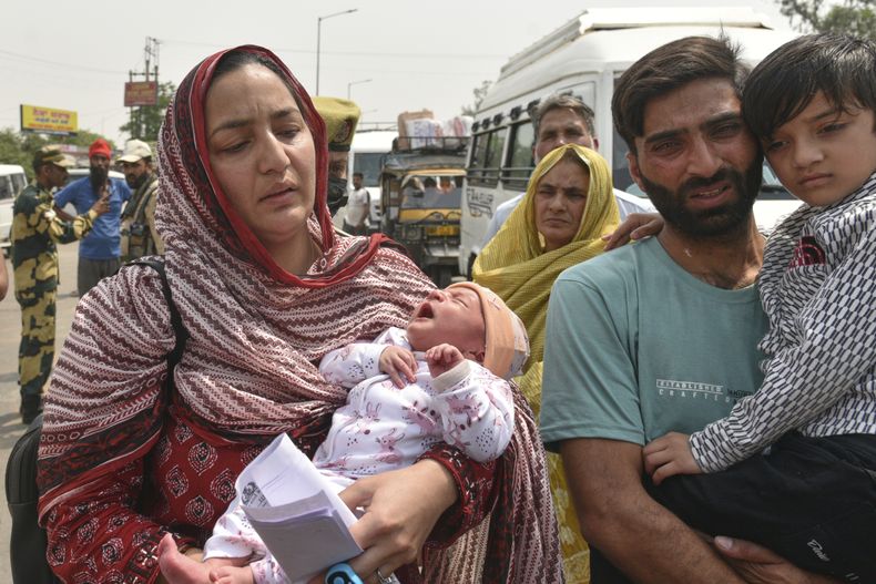 Sara Khan (izquierda), una ciudadana paquistaní casada con Aurangzeb Khan (derecha), que es ciudadano indio, --ambos con sus hijos en brazos-- se prepara para marcharse a su país sin su esposo, en el paso fronterizo de Attari-Wagah, entre India y Pakistán, el 30 de abril de 2025. (AP Foto/Prabhjot Gill)