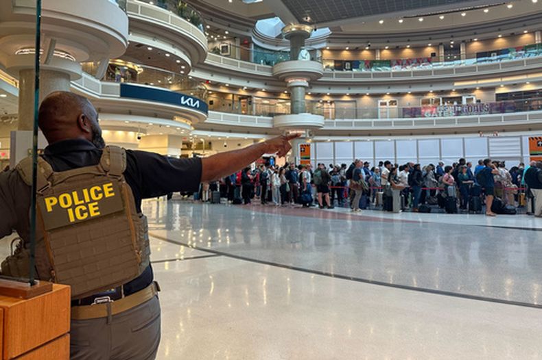 Un agente de inmigración se ve mientras gente espera en la línea del control de seguridad en el aeropuerto internacional de Hartsfield-Jackson Atlanta, el lunes 23 de marzo de 2026, en Atlanta. (AP Foto/Emilie Megnien)