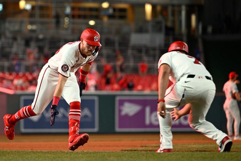 Curtis Mead, izquierda, de los Nacionales de Washington, es felicitado por el coach de tercera base Victor Estevez, derecha, después de batear un jonrón de dos carreras durante la séptima entrada del juego de béisbol de Grandes Ligas contra los Filis de Filadelfia, el lunes 22 de junio de 2026, en Washington. (AP Foto/John McDonnell)