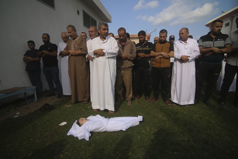 Familiares oran frente al cuerpo de Amir Ganan, quien murió a causa de un ataque aéreo israelí, durante su funeral, el martes 10 de octubre de 2023, en Jan Yunis, en la Franja de Gaza. (AP Foto/Hatem Ali)