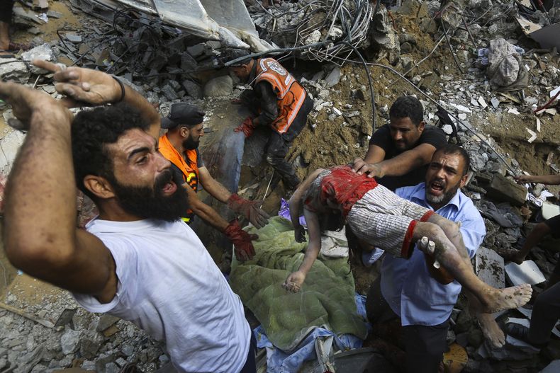 Palestinos trasladan el cuerpo sin vida de un niño, encontrado bajo los escombros de una casa destruida por los ataques israelíes sobre la Ciudad de Gaza, el 24 de octubre de 2023. (AP Foto/Abed Khaled)