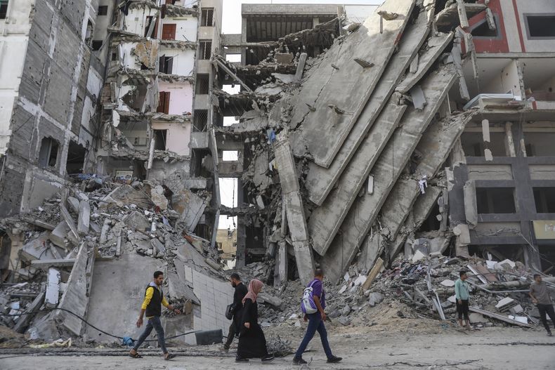 Palestinos caminan entre edificios en ruinas en la Ciudad de Gaza el 24 de noviembre de 2023, tras el inicio del alto el fuego entre Israel y Hamás. (AP Foto/Mohammed Hajjar)
