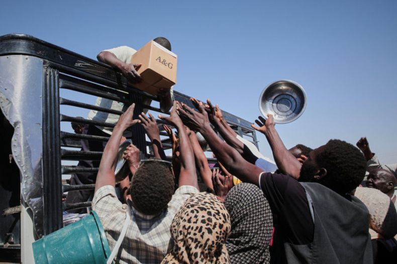 ARCHIVO - Familias sudanesas desplazadas de El-Fasher extienden las manos al tiempo que trabajadores humanitarios distribuyen alimentos en el recién establecido campamento de El-Afadh, en Al Dabbah, estado del Norte, Sudán, el 16 de noviembre de 2025. (Foto AP/Marwan Ali, archivo)