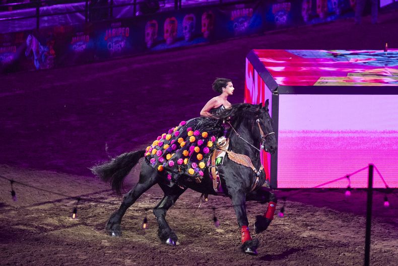 Ángela Aguilar, hija de Pepe Aguilar, monta un caballo al cantar en el espectáculo Jaripeo hasta los huesos tour 2024 en el Honda Center en Anaheim, California, el viernes 29 de marzo de 2024. El espectáculo rinde homenaje al Día de Muertos, una conocida celebración mexicana. (Foto AP/Damian Dovarganes)