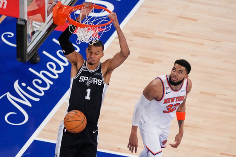 Victor Wembanyama (1), de los Spurs de San Antonio, clava el balón mientras Karl-Anthony Towns (32), de los Knicks de Nueva York, observa durante la segunda mitad del tercer juego de las Finales de la NBA, el lunes 8 de junio de 2026, en Nueva York. (AP Foto/Yuki Iwamura)