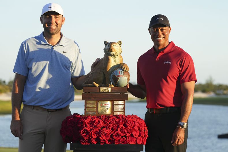 Scottie Scheffler, izquierda, de Estados Unidos, y Tiger Woods, posan con el trofeo del campeonato después de la ronda final del torneo Hero World Challenge del PGA Tour, en el Club de Golf Albany, en New Providence, Bahamas, el domingo 8 de diciembre de 2024. (AP Foto/Fernando Llano)
