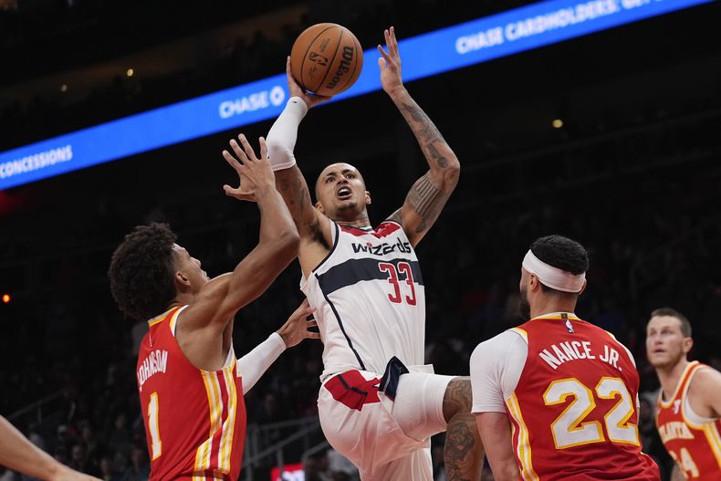 Kyle Kuzma (33), de los Wizards de Washington, se alza para disparar mientras observan Jalen Johnson (1) y Larry Nance Jr. (22), de los Hawks de Atlanta, durante la segunda mitad del juego de baloncesto de la NBA, el lunes 28 de octubre de 2024, en Atlanta. (AP Photo/ John Bazemore)
