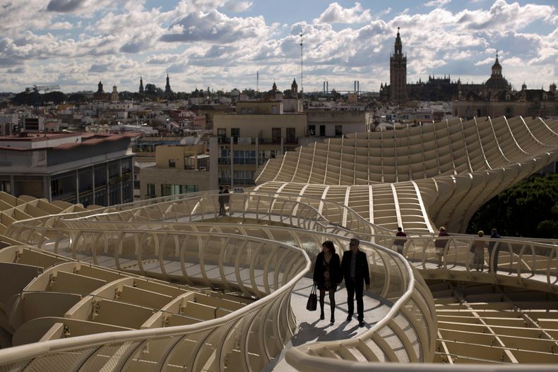 Una pareja camina por uno de los corredores del Metropol Parasol, desde donde se ve la ciudad antigua y la Catedral de Sevilla con La Giralda en España, el 18 de noviembre de 2012. La Academia Latina de la Grabación anunció el 4 de mayo de 2023 que la 24a ceremonia del Latin Grammy se celebrará el 16 de noviembre en esta ciudad del sur de España. (Foto AP/Emilio Morenatti, archivo)