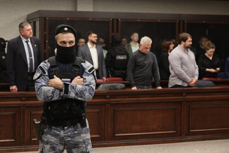 Personas juzgadas por terrorismo por el ataque de 2022 al puente que une a Rusia con Crimea, anexada por Moscú, permanecen en una celda de cristal, de espaldas, en un tribunal militar en Rostov del Don, Rusia, el jueves 27 de noviembre de 2025. (Foto AP)