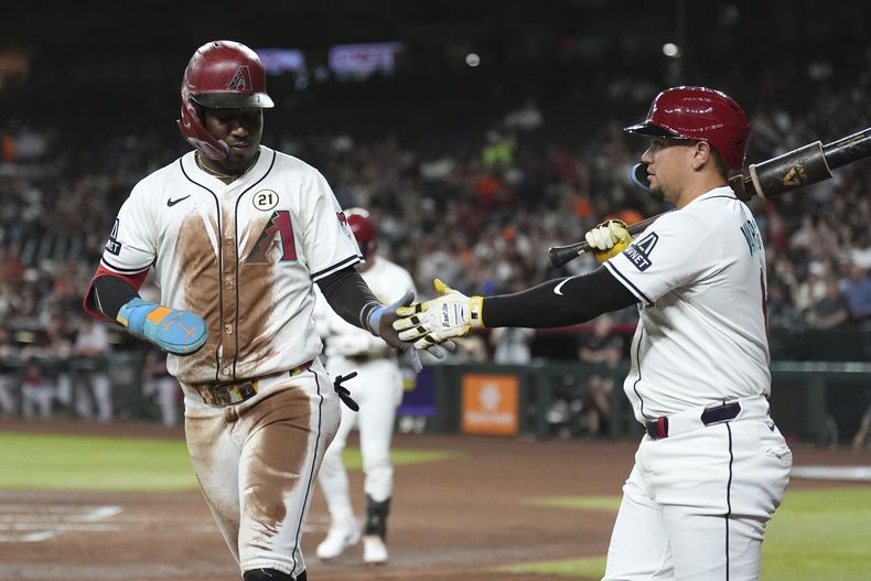 Geraldo Perdomo, izquierda, de los Diamondbacks de Arizona, celebra una carrera anotada frente a los Gigantes de San Francisco con su compañero Ildemaro Vargas, derecha, durante la primera entrada del juego de béisbol de Grandes Ligas, el lunes 15 de septiembre de 2025, en Phoenix. (AP Foto/Ross D. Franklin)