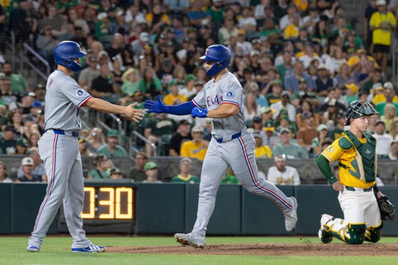 Wyatt Langford, de los Rangers de Texas, recibe la felicitación de Corey Seager luego de batear un jonrón de dos carreras ante los Atléticos, el sábado 15 de agosto de 2026 (AP Foto/Sara Nevis)