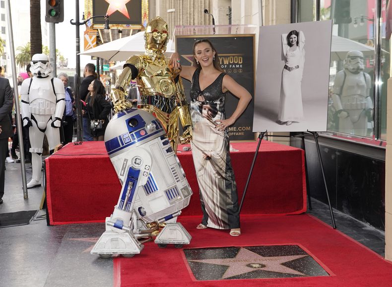 Billie Lourd, hija de la fallecida a actriz Carrie Fisher, derecha, posa con la estrella de Fisher en el Paseo de la Fama de Hollywood junto a los personajes de las películas de Star Wars C-3PO y R2-D2, durante una ceremonia póstuma en Los Angeles el jueves 4 de mayo de 2023. La fecha se conoce también como Día de Star Wars, en homenaje a las películas de Star Wars en las que Fisher interpretó a la Princesa Leia. (Foto AP/Chris Pizzello)