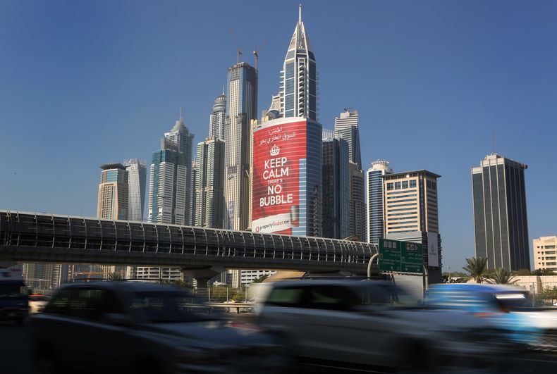 En esta foto del mi&eacute;rcoles 13 de noviembre de 2013, veh&iacute;culos pasan junto a una torre con un cartel que afirma "tranquilos, no hay burbuja", en el distrito Marina de Dubai, Emiratos Arabes Unidos. Dubai ser&aacute; anfitriona de la