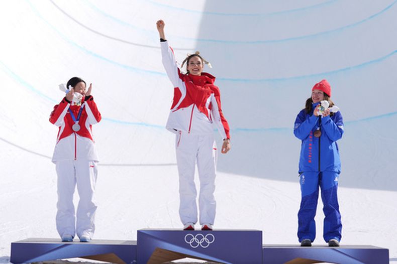 Eileen Gu, que representa a China, posa con en el centro flanqueada por la china Li Fanghui (plata) y la británica Zoe Atkin (bronce) tras la prueba de halfpipe freestyle en los Juegos Olímpicos de Invierno el domingo 22 de febrero del 2026. (AP Foto/Abbie Parr)