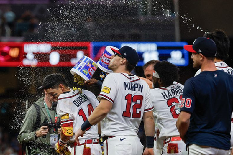 Mauricio Dubón, izquierda, de los Bravos de Atlanta, es celebrado por sus compañeros después de batear un sincillo productor de la carrera del triunfo frente a los Rojos de Cincinnati durante la 10ma entrada del juego de béisbol de Grandes Ligas, el miércoles 23 de septiembre de 2026, en Atlanta. (AP Foto/Erik S. Lesser)