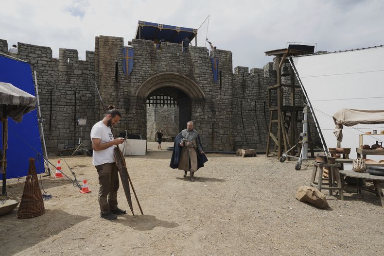Trabajadores y artistas en el set de la serie de diez episodios Robin Hood, en Belgrado, Serbia, el lunes 5 de mayo de 2025. (Foto AP/Darko Vojinovic)